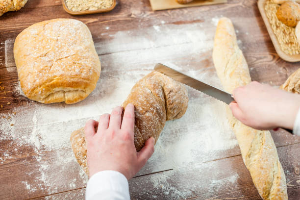 木製のテーブル、選択と集中に焼きたてのパンを切る男性の手 - brown bread bread cutting board full length ストックフォトと画像