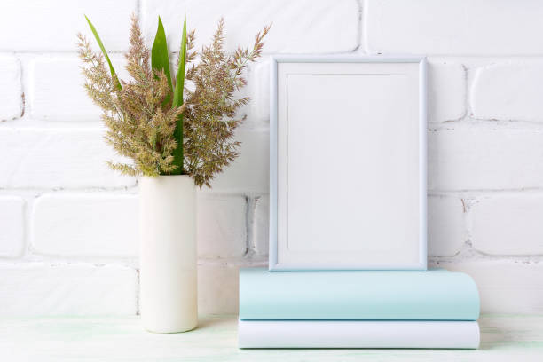 istock White frame mockup with  grass and green leaves in cylinder vase 833170854
