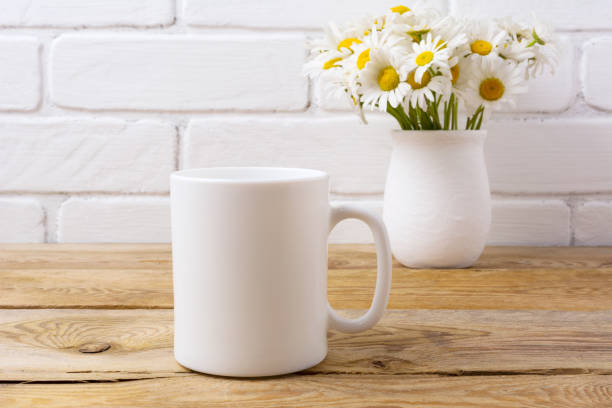 istock White coffee mug mockup with chamomile bouquet in rustic vase 833171258