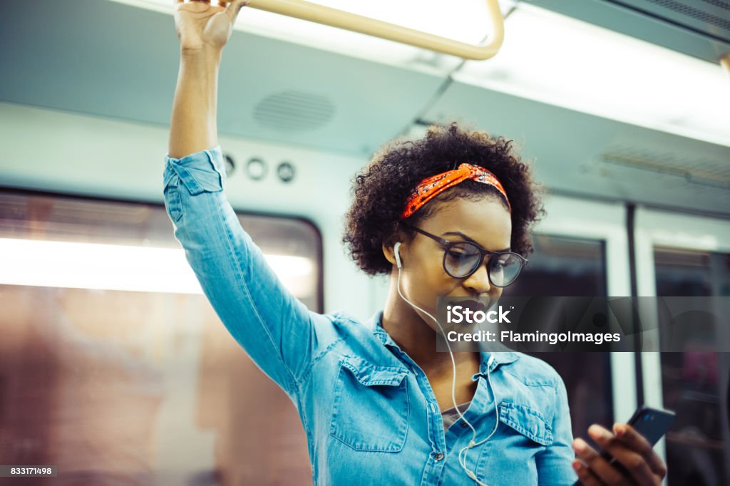 Souriante jeune femme africaine, écouter de la musique dans le métro - Photo de Femmes libre de droits