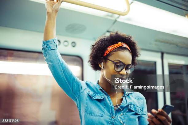 Photo libre de droit de Souriante Jeune Femme Africaine Écouter De La Musique Dans Le Métro banque d'images et plus d'images libres de droit de Femmes