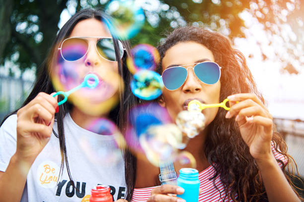 istock Carefree girlfriends playing with bubble wands outside in summer 833176092