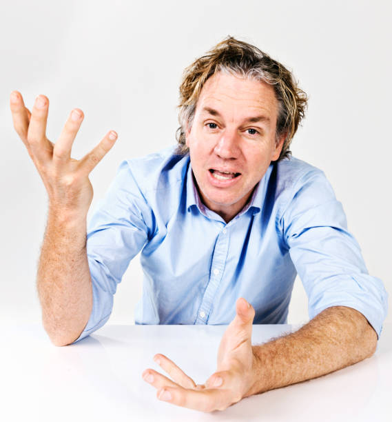 istock Mid-adult man behind desk gesturing expressively 833186880