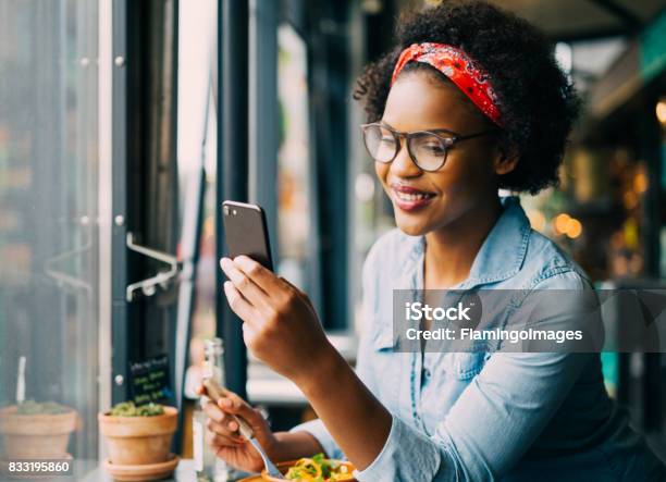 Donna Sorridente Che Legge Messaggi Di Testo A Cena In Un Bistrot - Fotografie stock e altre immagini di Donne