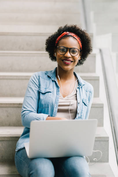 istock Smiling young African entrepreneur sitting on stairs using a laptop 833198304