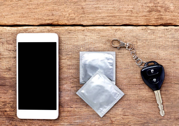 istock condoms, key and mobile phone on wooden table. 833211426