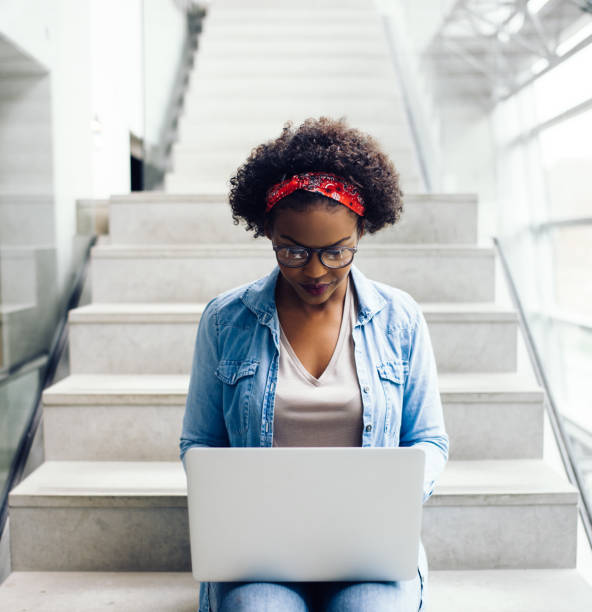 istock Young African entrepreneur sitting on office stairs using a laptop 833216894