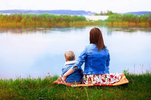 istock Mother with a child on the river bank 833217100