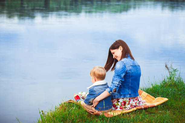 istock Mother with a child on the river bank 833217170