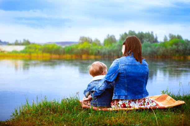 istock Mother with a child on the river bank 833217636