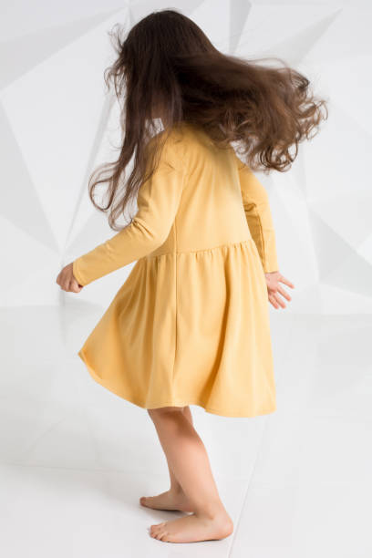mała dziewczynka ubrana w żółtą sukienkę tańczącą w studio na białym tle - male vertical photography studio shot zdjęcia i obrazy z banku zdjęć