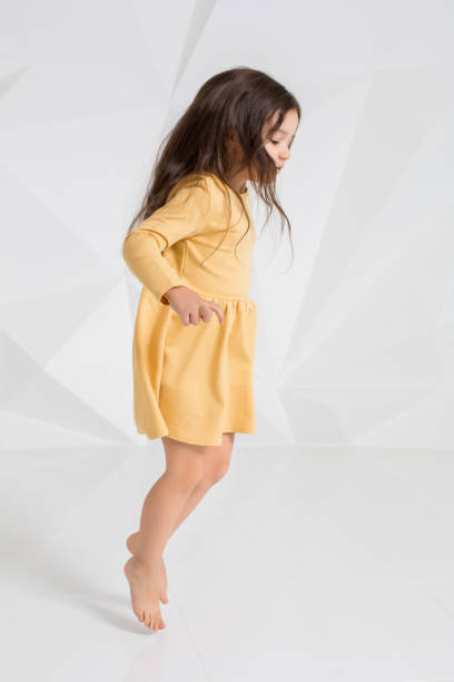 mała dziewczynka ubrana w żółtą sukienkę tańczącą w studio na białym tle - male vertical photography studio shot zdjęcia i obrazy z banku zdjęć