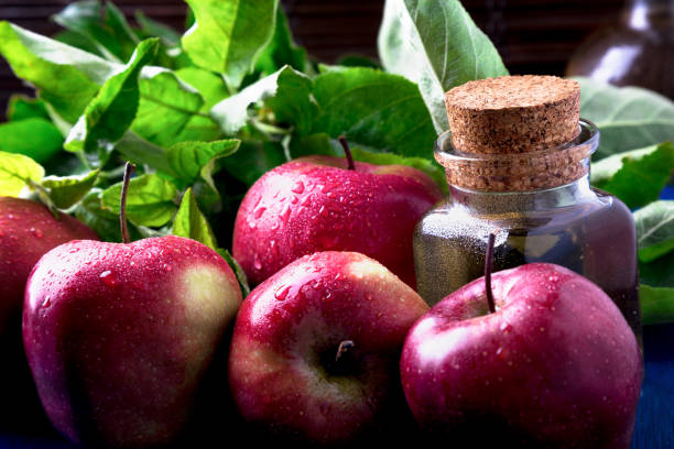 istock Apple cider vinegar. One glass bottle on blue background. Red apples. 833221170