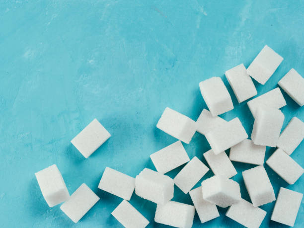 istock Top view of white sugar cubes on blue concrete background 833229770