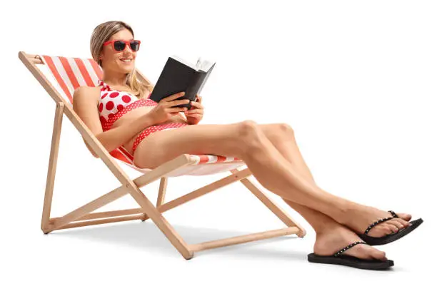 Photo of Young woman reading a book in a deck chair