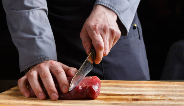 istock Chef cutting filet mignon on wooden board at restaurant kitchen 833236970