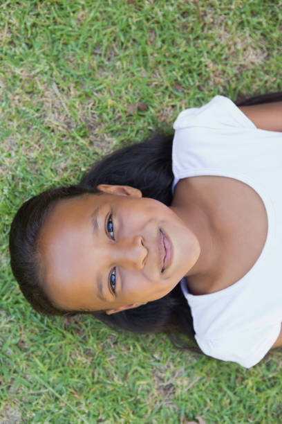 istock Little girl lying on the grass smiling at camera 833237364
