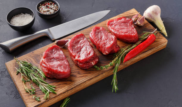 istock Filet mignon steaks and spices on wood at black background 833237574