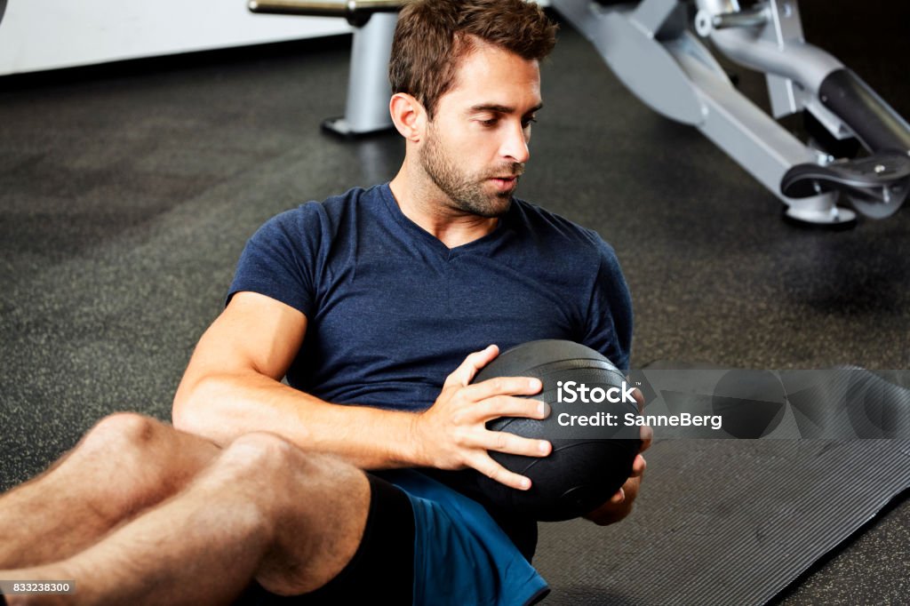 Fit guy in gym Fit guy doing sit-ups with weight in gym Gym Stock Photo
