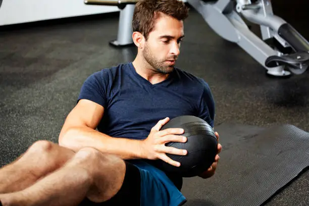 Fit guy doing sit-ups with weight in gym