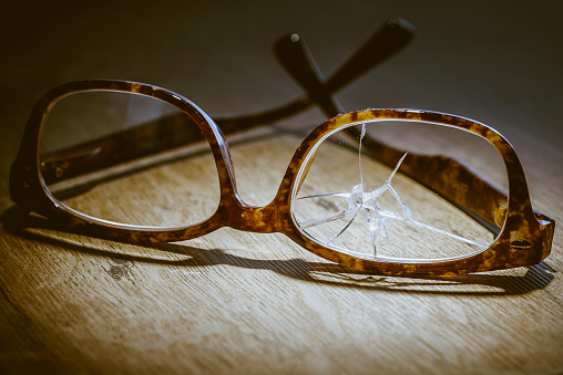 Broken eyeglasses on wooden floor