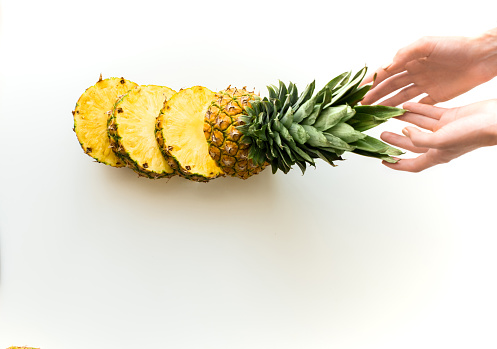 top view of hands with sliced fresh pineapple, isolated on white