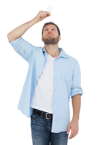 Sceptical model holding a bulb above his head Sceptical model on white background holding a bulb above his head man with a light bulb over his head stock pictures, royalty-free photos & images