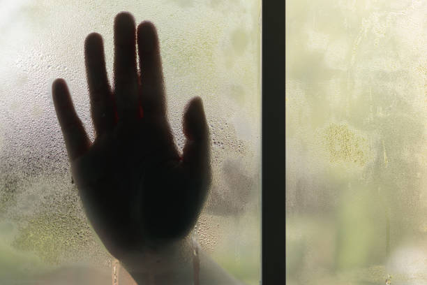 istock Silhouetted palm of hand, behind the window, selective focus on drop water and surface on glass. Scream for help, halloween day, depression, stress, panic concept. 833252038