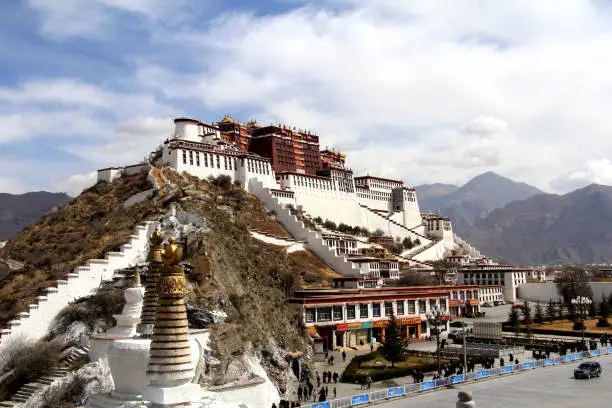 the panoramic of the Potala Palace, with the people republic of China flag inside as well as Potala Palace square, trees and meadow, Tibet Admiralty, golden chimes and Colored prayer