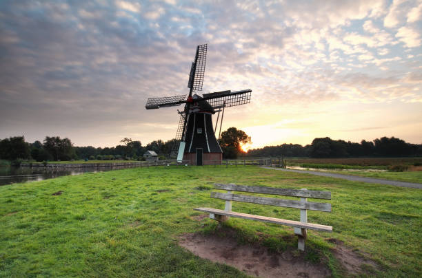 wooden bench near windmill at sunrise, Netherlands