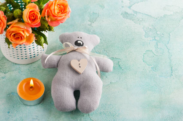 istock Fresh orange roses flowers, teddy bear and lit candle 833281570