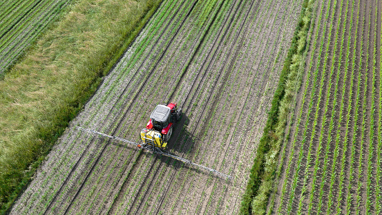 Aerial view of crop sprayer spraying pesticides on crops in field.