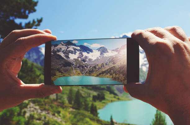 smartphone in hand photographing a mountain lake in the dolomites