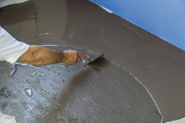 istock Worker puts a self leveling screed with tool on concrete floor. House under construction 833289780