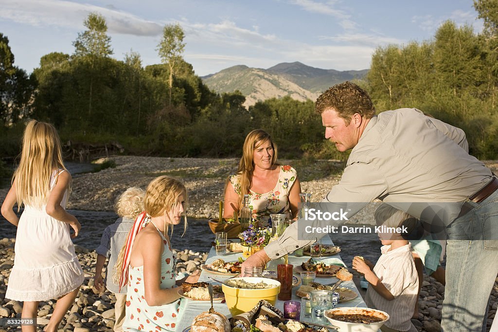 Family dinner outdoors Family dinner outdoors by river at sunset Family Stock Photo