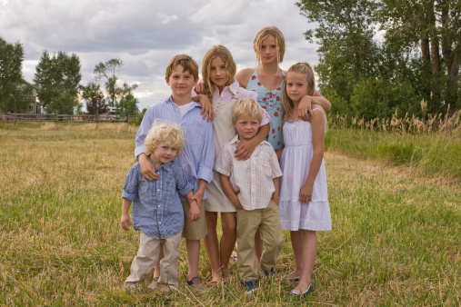 Portrait of brothers and sisters standing in field
