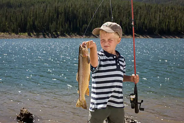 Photo of Boy holding up fish he caught