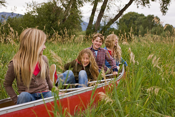 enfants jouant dans un canoë sur la terre - montana outdoor pursuit canoe canoeing photos et images de collection