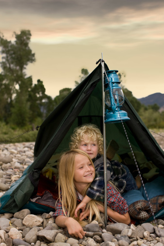 Sibling camping outdoors with mountain view