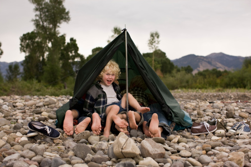 Youngest brother horsing around with siblings in tent with mountain view