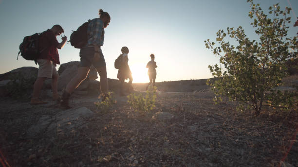Anonymous group of travelers with backpacks coming to coast and posing happily.