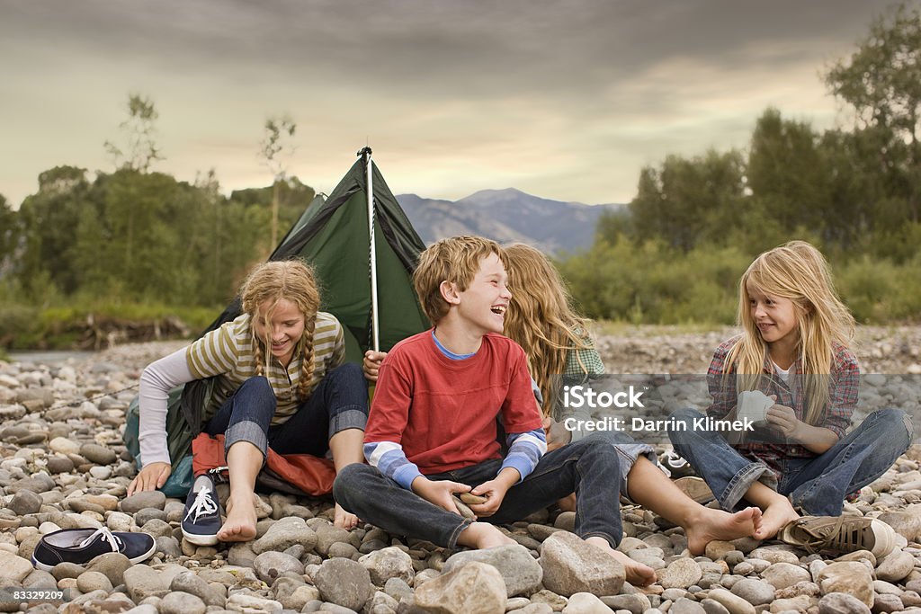 Brother and sisters playing in small tent Brother and sisters playing outdoors around small pup tent along a creek Child Stock Photo