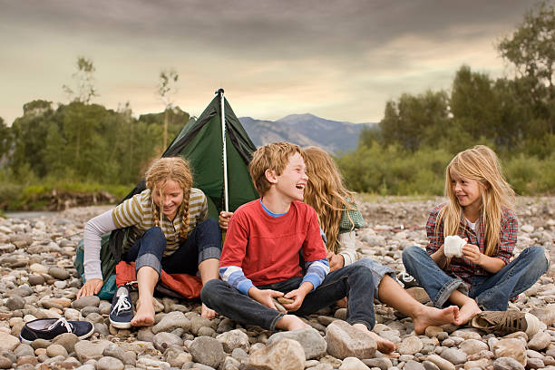 Brother and sisters playing in small tent Brother and sisters playing outdoors around small pup tent along a creek travel9 stock pictures, royalty-free photos & images