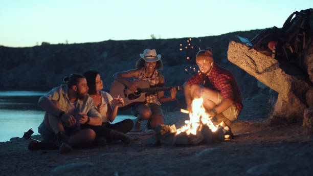 voyageur relaxant au feu de joie sur terre - camping friendship campfire fire photos et images de collection