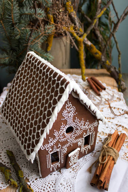 Gingerbread house, homemade, with Christmas tree in background, vertical