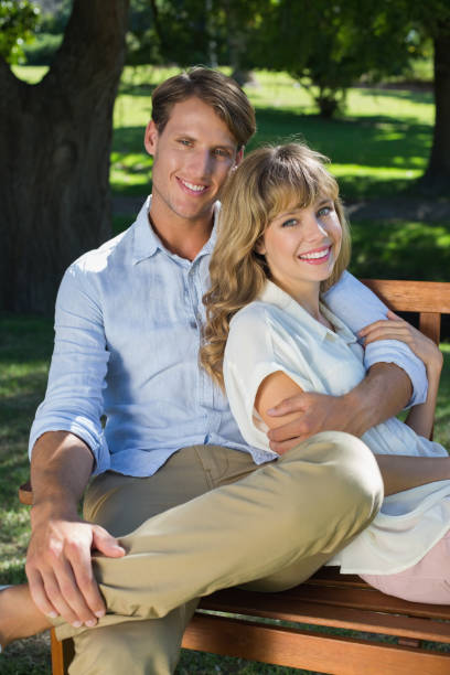 istock Affectionate couple relaxing on park bench together smiling at camera 833307688