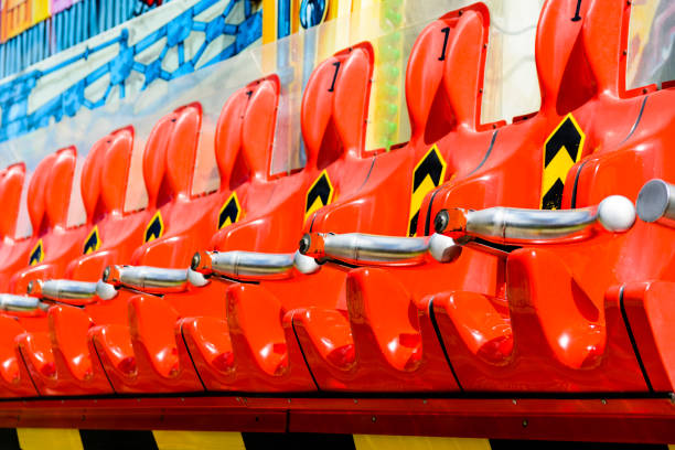 Row of empty vivid red seats of a thrilling ride at a funfair Row of empty vivid red seats of a thrilling ride at a funfair. roller coaster line photos stock pictures, royalty-free photos & images