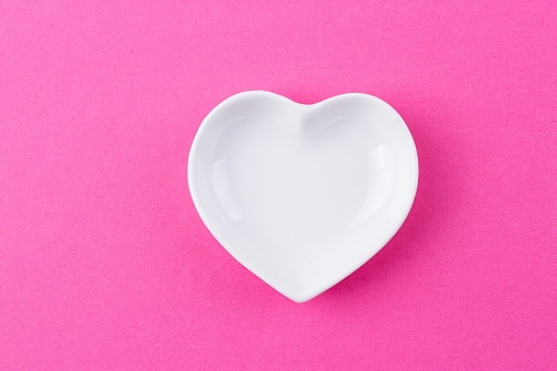 White plate in the shape of heart on a pink background