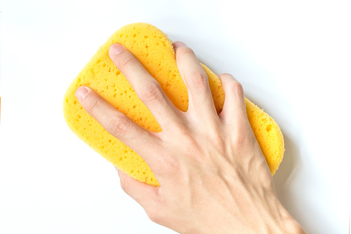 close-up of Hand holding yellow Sponge for Car Wash isolated on white background