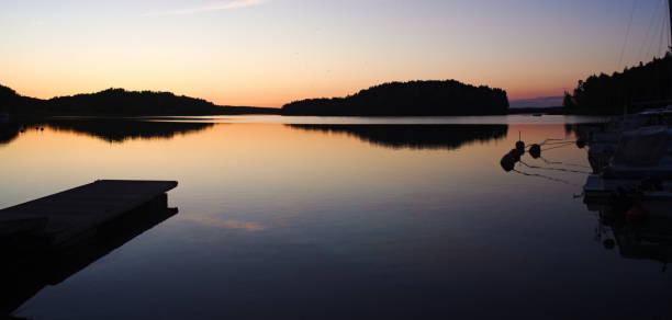 une jetée reflétée dans l’eau calme à empreintes de coucher de soleil, humides sur la jetée - lakedistrict photos et images de collection